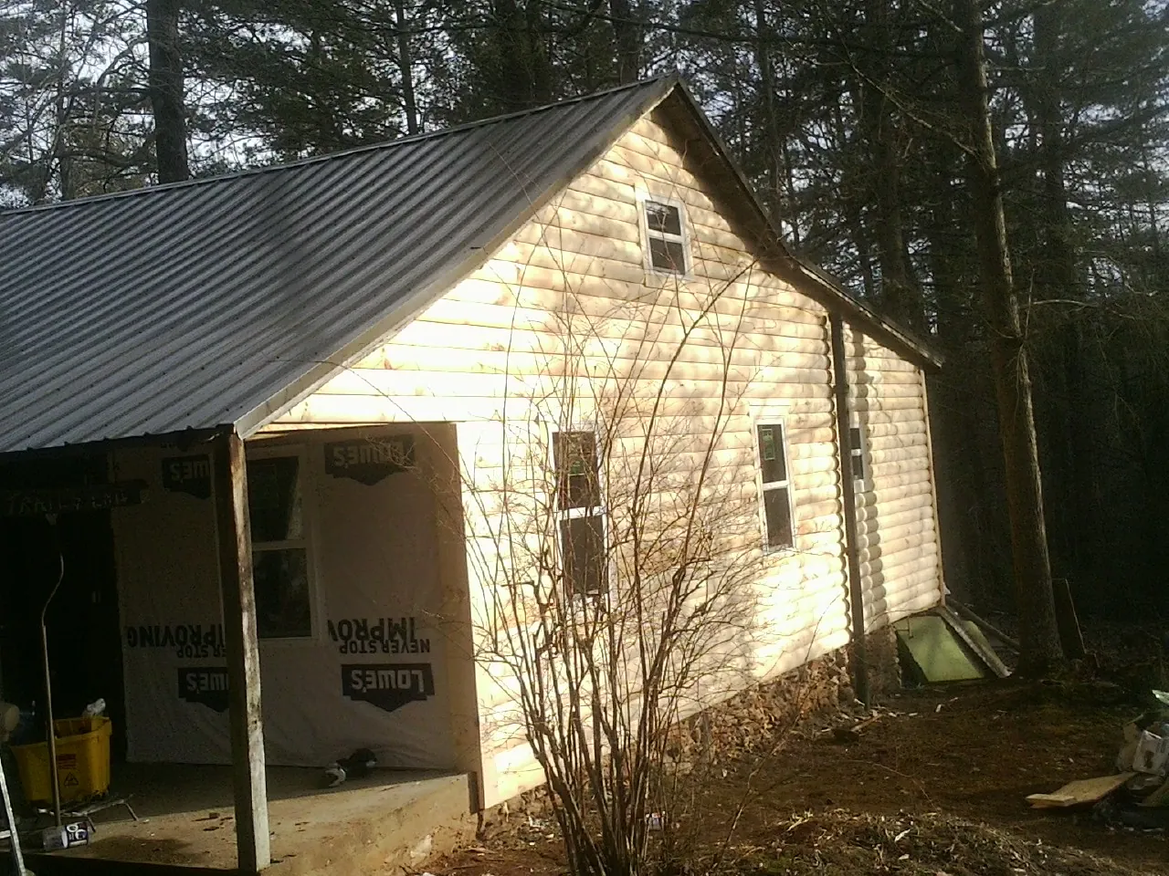 Log siding gable end under a dark metal roof edge in Anthony