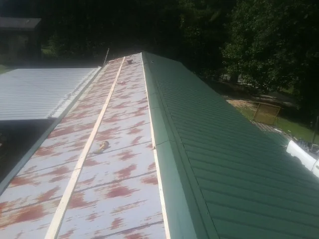 Old rusted panels beside newly installed green metal roofing — Wind Damage Roof Repair by Roofing Brothers in Anthony