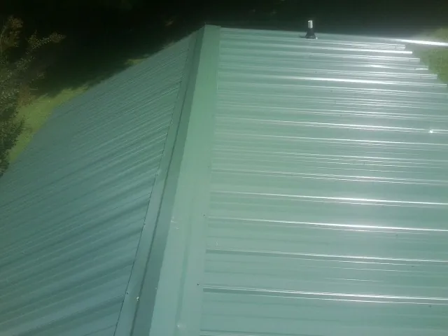 New green metal panels meeting at the ridge of a roof — Flat Roof Repair work by our crew in Anthony