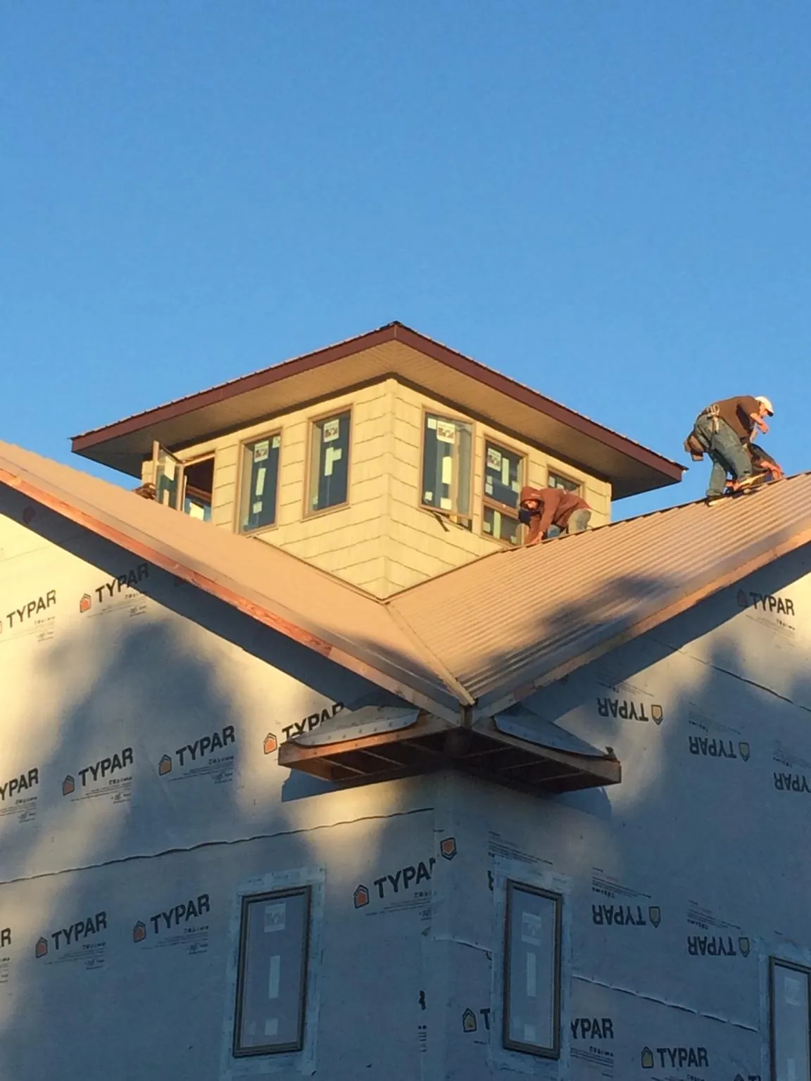 Roofers working around a rooftop cupola on a new metal roof at sunset — Roof Waterproofing in Anthony by Roofing Brothers